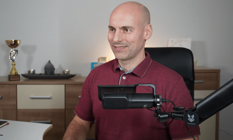 Der österreichische positionierungs-Experte Andreas Mayr-Stockinger lächelnd vor einem Podcast-Mikrofon
